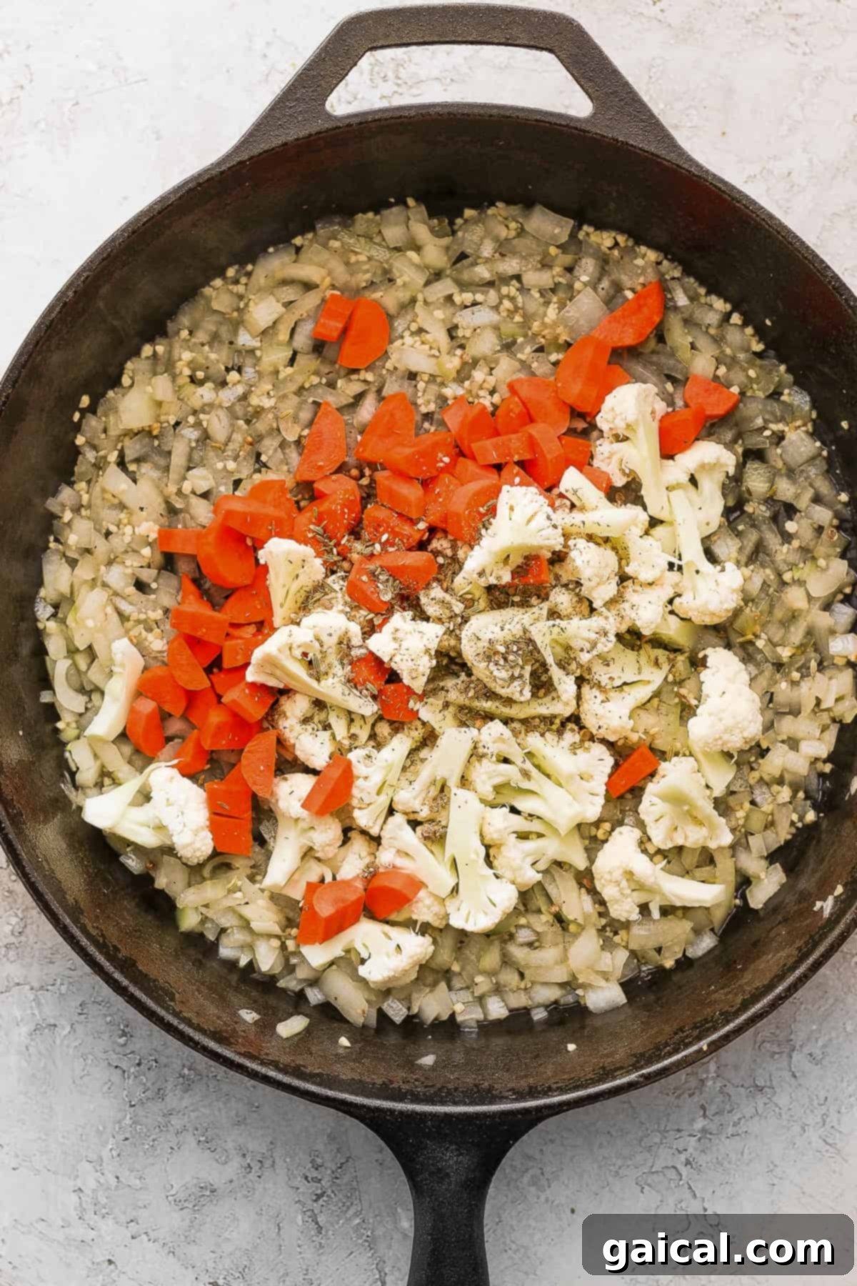 Effortless Za'atar Meatball Quinoa Skillet 6 Colorful carrots and cauliflower florets sautéing in a cast iron skillet, seasoned with spices, forming the vegetable base for the One-Pot Za'atar Meatballs and Quinoa.