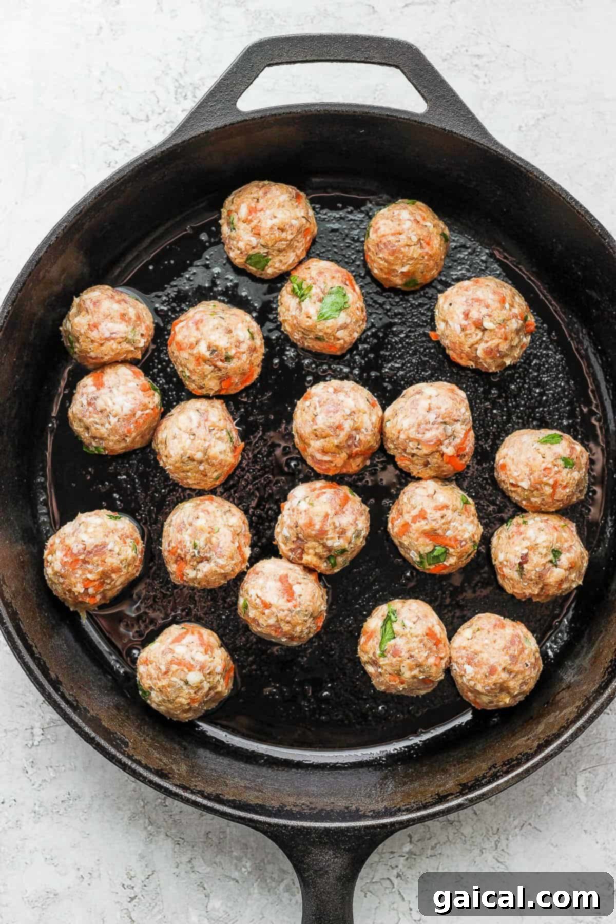 Effortless Za'atar Meatball Quinoa Skillet 5 Golden-brown Za'atar meatballs sizzling in a hot cast iron skillet, acquiring a delicious crust before being fully cooked, showcasing the first step of the one-pot recipe.