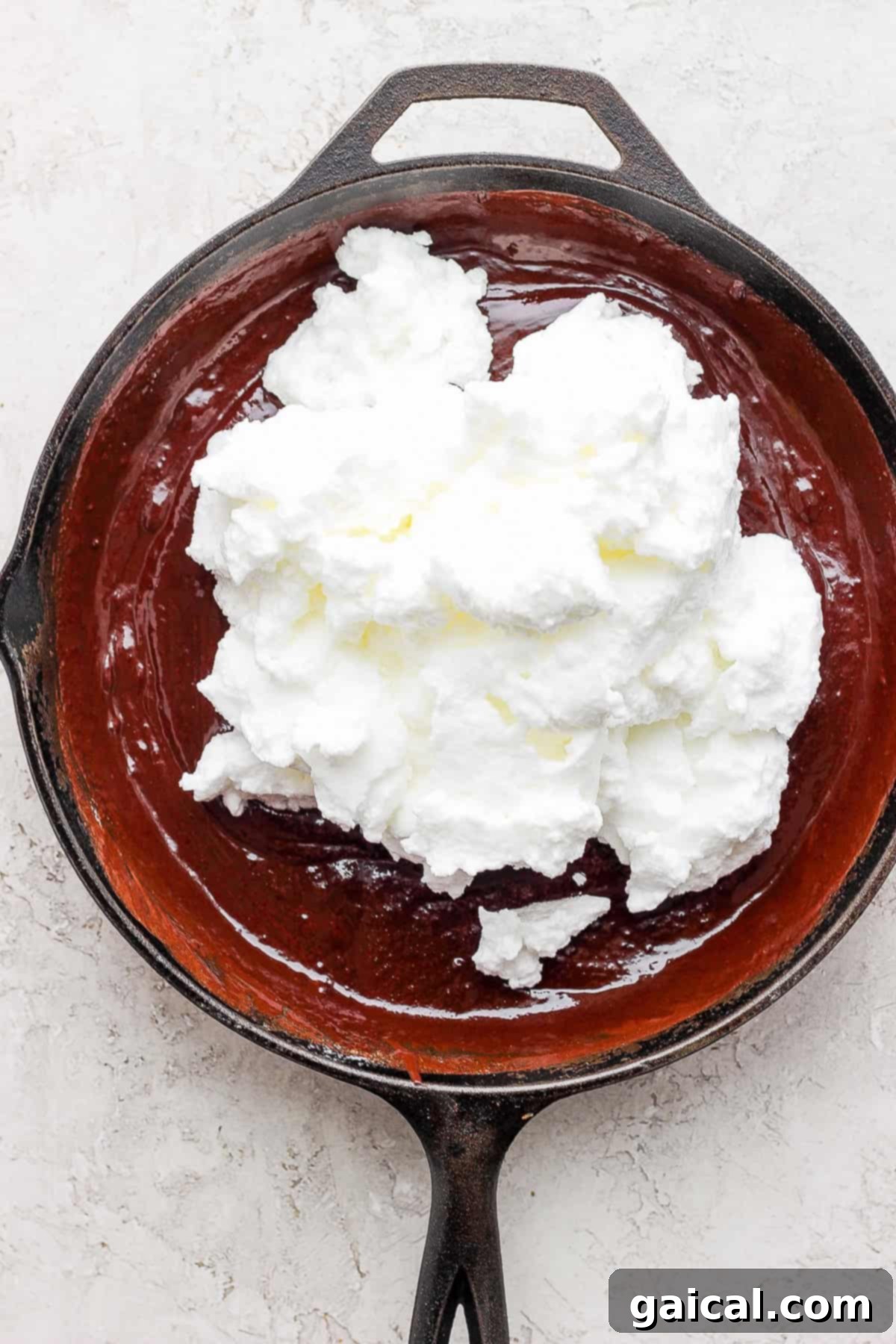 Folding Egg Whites into Batter Softly folded egg whites being gently incorporated into the rich chocolate skillet cake batter.