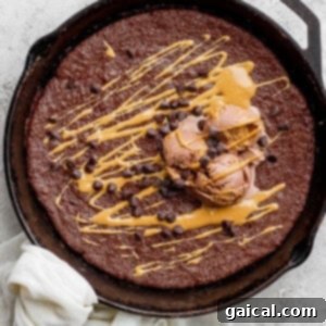 Flourless chocolate skillet cake with a scoop of ice cream on top.