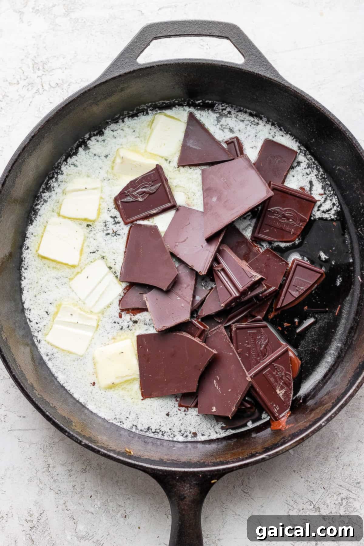 Melting Chocolate and Butter Bittersweet chocolate and unsalted butter melting gently together in a cast iron skillet over low heat.