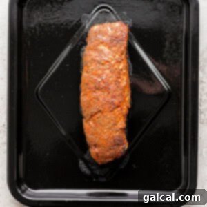 A seasoned pork tenderloin placed inside an air fryer basket, ready for cooking.