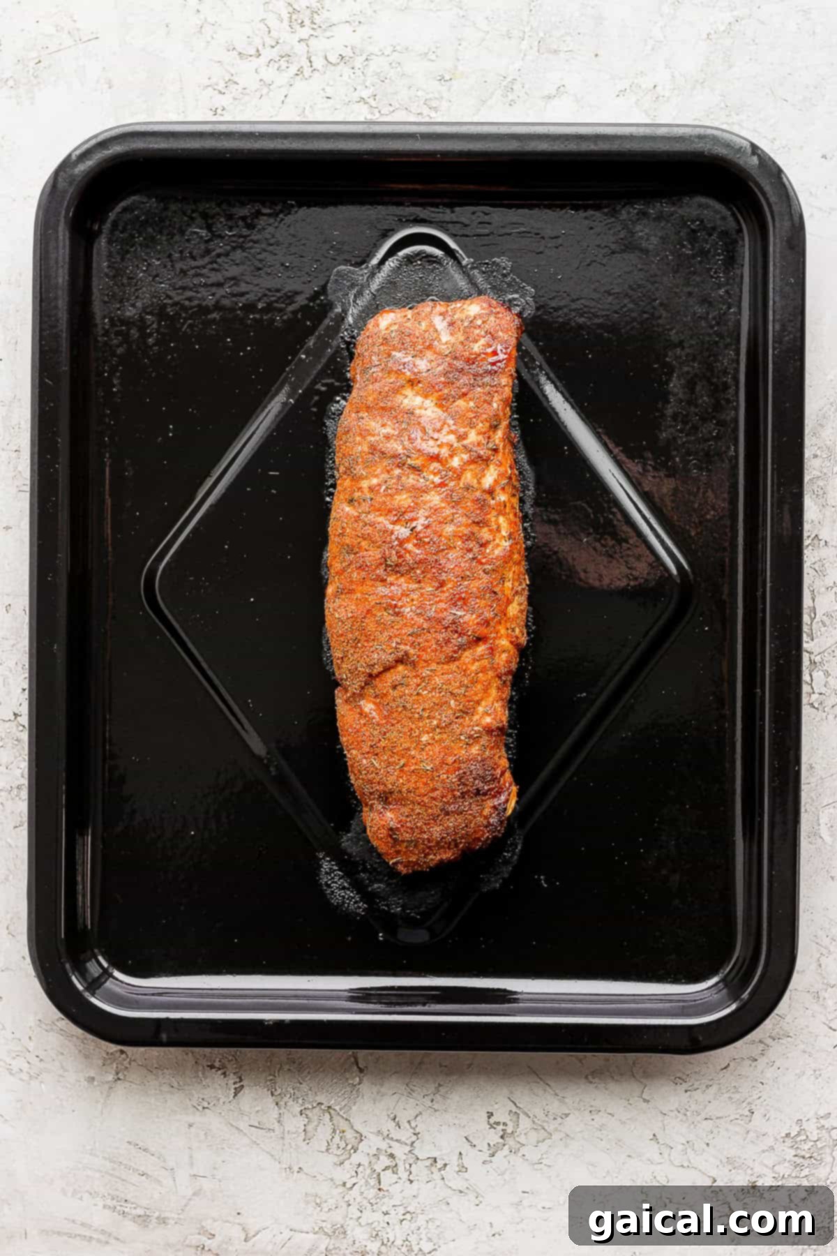 This Air Fryer Pork Tenderloin recipe is super moist on the inside with a crispy outside and is ready to enjoy in minutes. A raw pork tenderloin seasoned and placed inside an air fryer basket, ready for cooking.