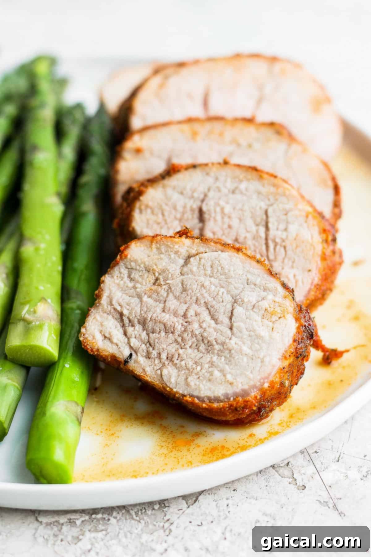This Air Fryer Pork Tenderloin recipe is super moist on the inside with a crispy outside and is ready to enjoy in minutes. Air fryer pork tenderloin sliced into thick medallions, beautifully arranged on a white plate, showcasing its juicy interior.