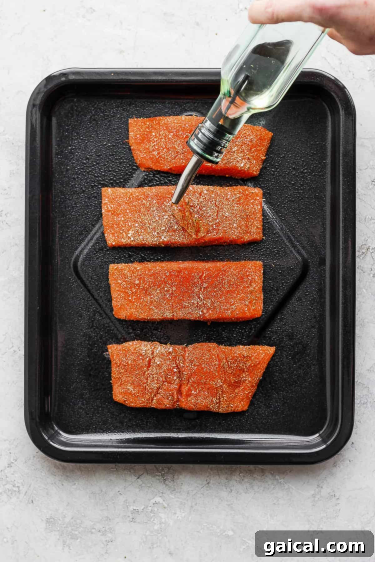 Raw salmon fillets being drizzled with olive oil before air frying, ensuring a crispy finish.