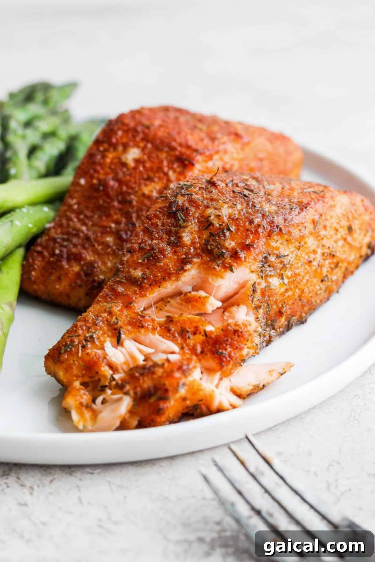 Close-up of flaky air fryer salmon on a plate, demonstrating its perfectly cooked texture.