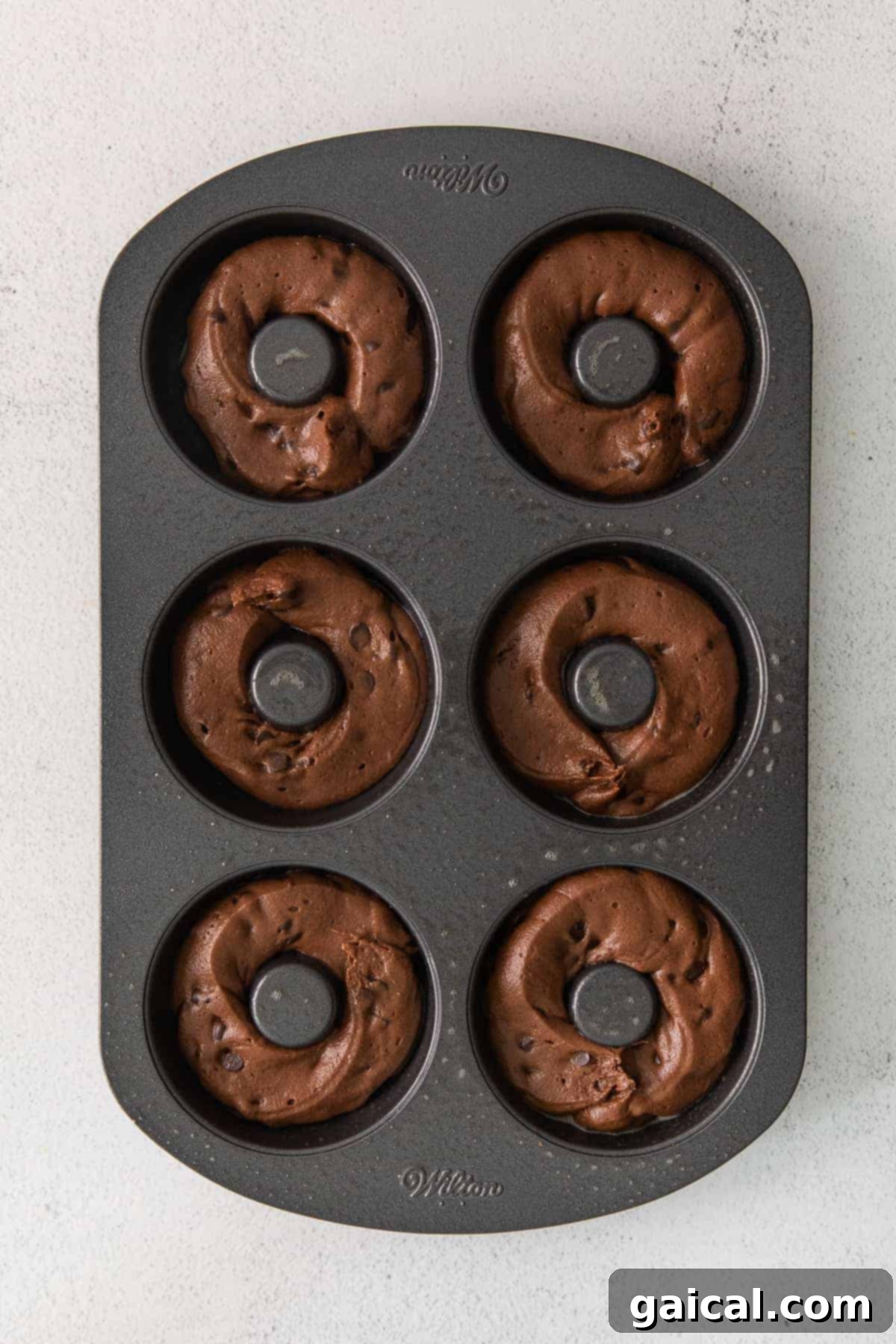 Piping Donut Batter into Pan Chocolate donut batter being piped into a donut baking pan