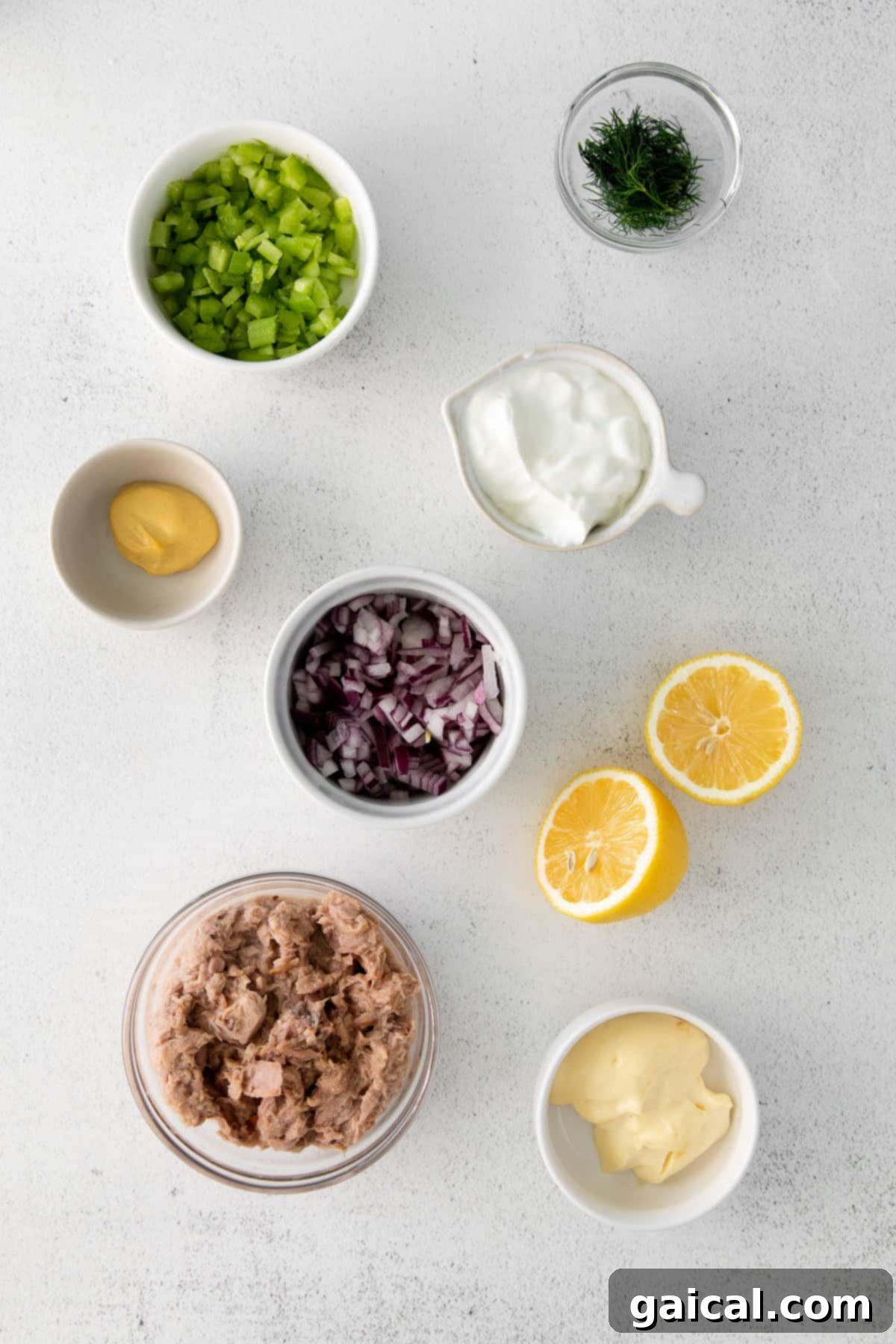 Bowls filled with fresh, vibrant ingredients including canned tuna, finely diced red onion, and chopped celery, perfectly arranged and ready for mixing into a healthy tuna salad.