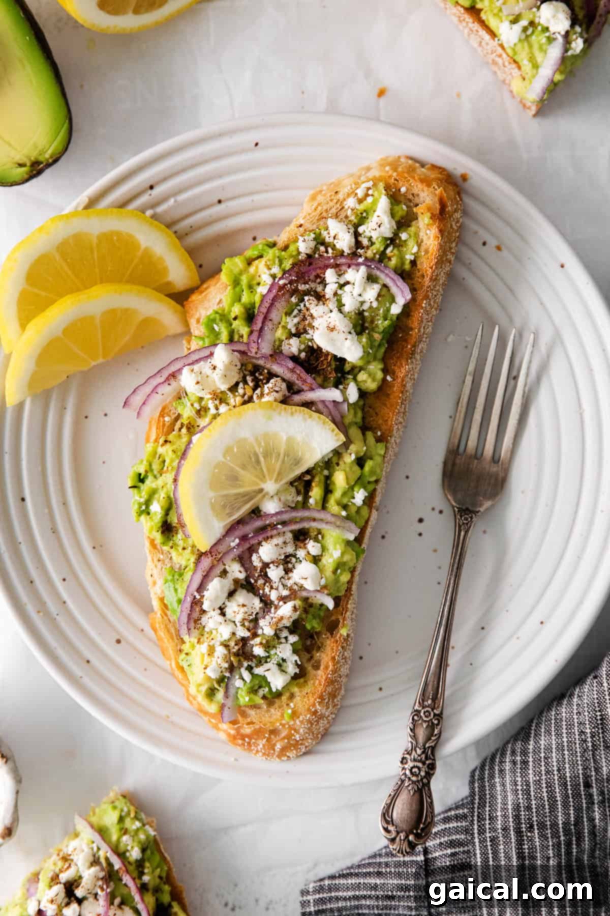 Mediterranean avocado toast adorned with feta, red onion, and za'atar on a plate