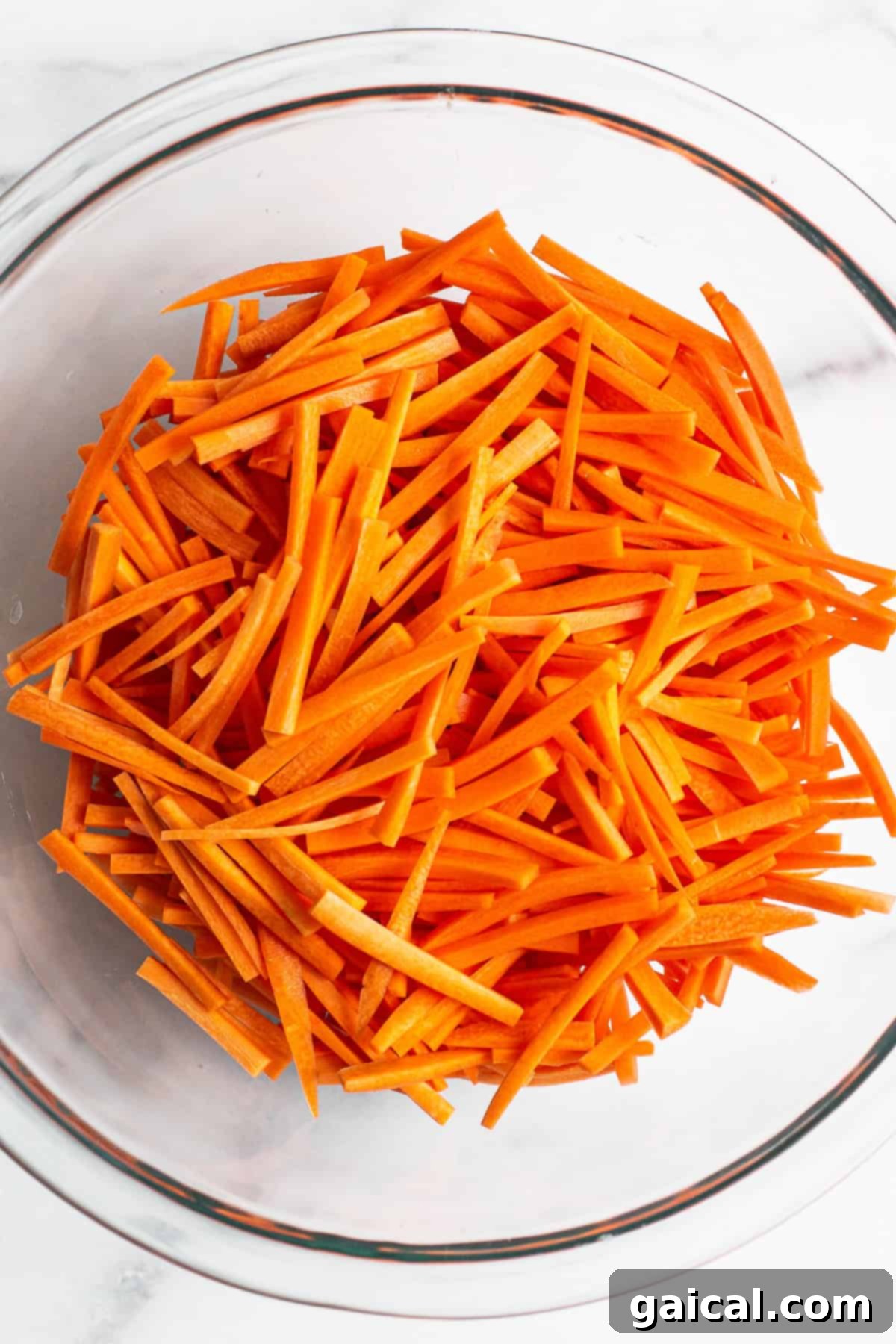 Freshly cut julienned carrots in a glass bowl, ready to be transformed into a delicious salad.