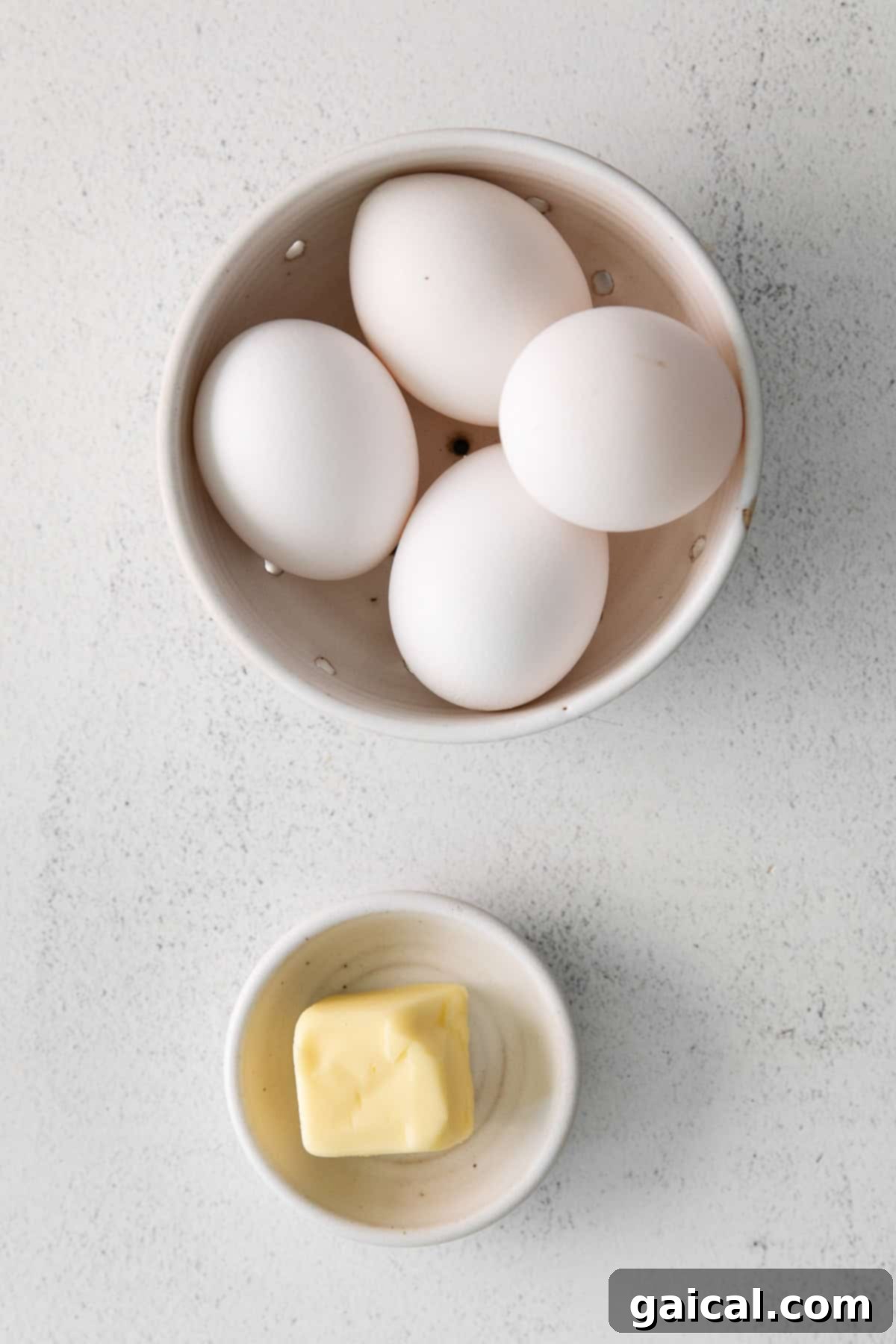 Fry the Perfect Egg 3 Four large, fresh eggs nestled in a white ceramic bowl, ready for frying.