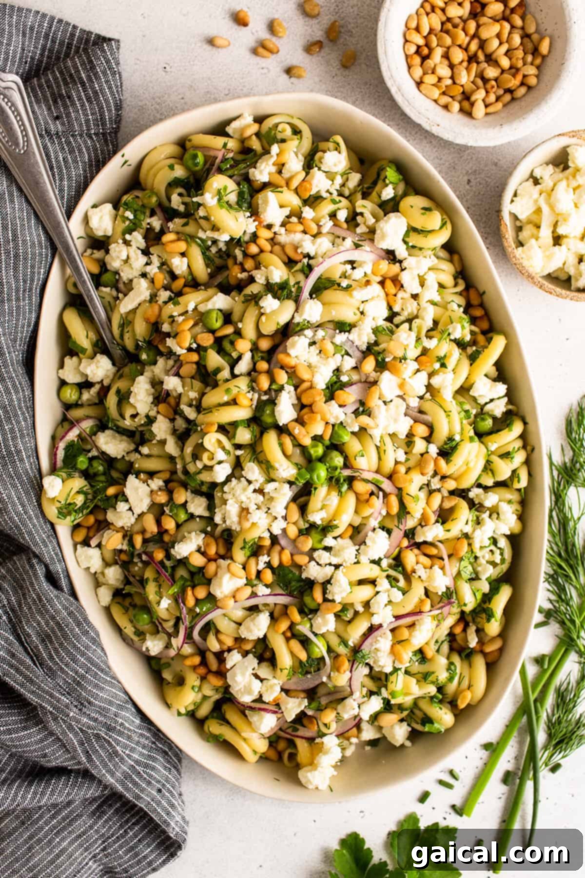 Delicious Lemon Pasta Salad with Fresh Herbs, Feta, and Pine Nuts Large bowl of lemon pasta salad, garnished with vibrant fresh herbs, crumbled feta, and toasted pine nuts