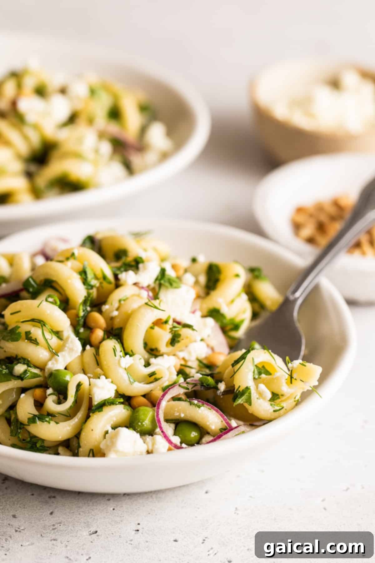Ready-to-Serve Lemon Pasta Salad Serving bowl of lemon pasta salad, artfully topped with fresh herbs and toasted pine nuts, ready to be enjoyed