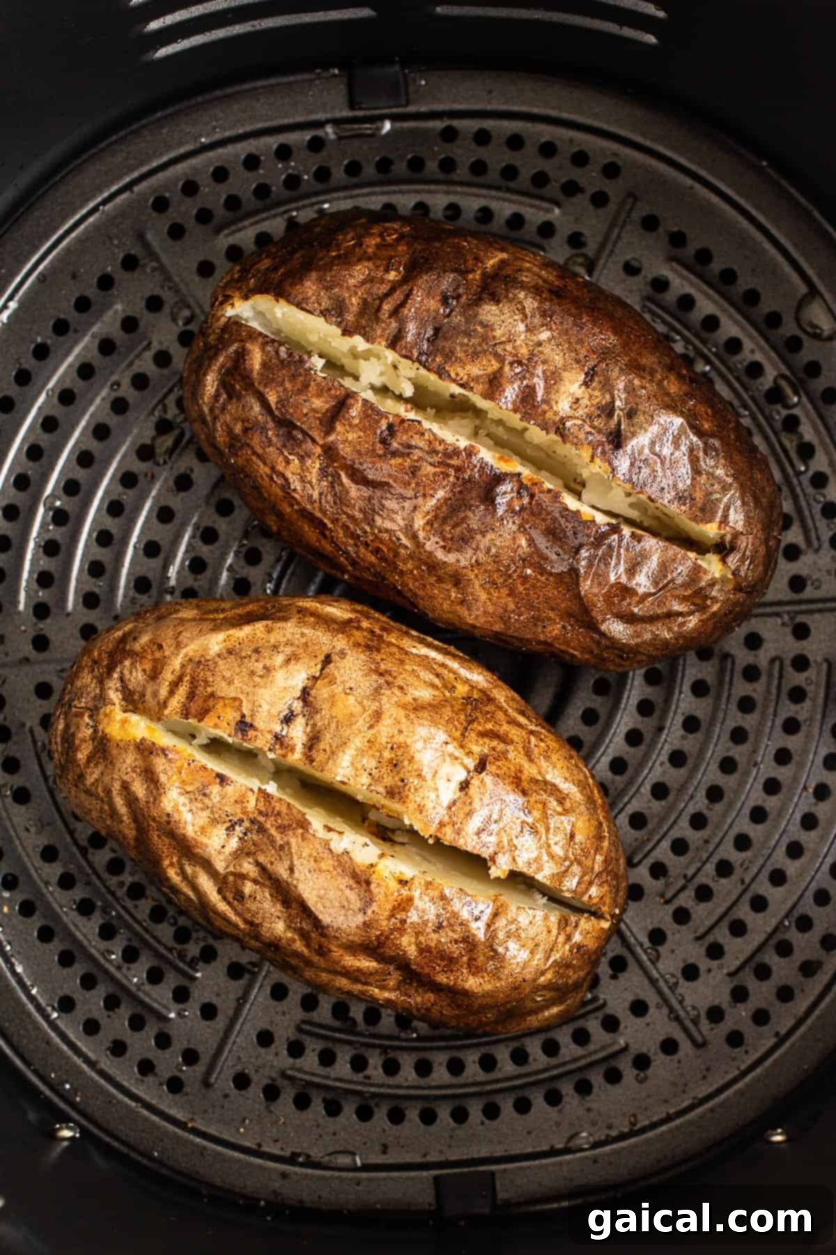 A close-up shot of a perfectly air-fried baked potato, split open, with visible steam and a fork ready to fluff the tender interior.