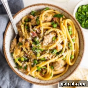 A bowl of pasta with chicken and parsley.