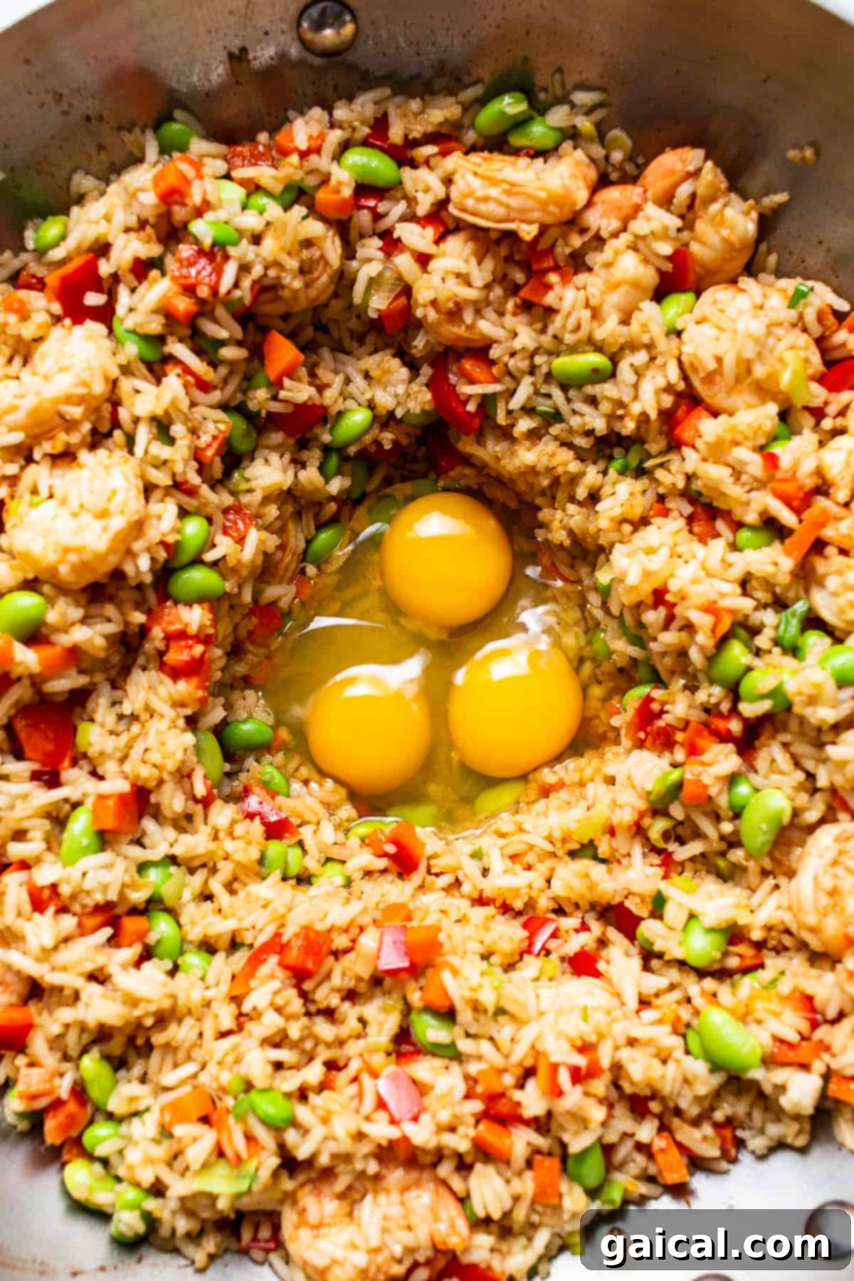Integrating Eggs into Fried Rice for Perfect Texture Scrambling large, fluffy eggs in a clear well created within the fried rice mixture in a pan.