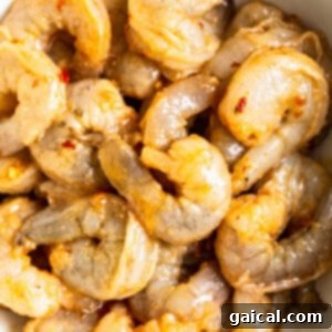 Uncooked shrimp marinating in a bowl with spices