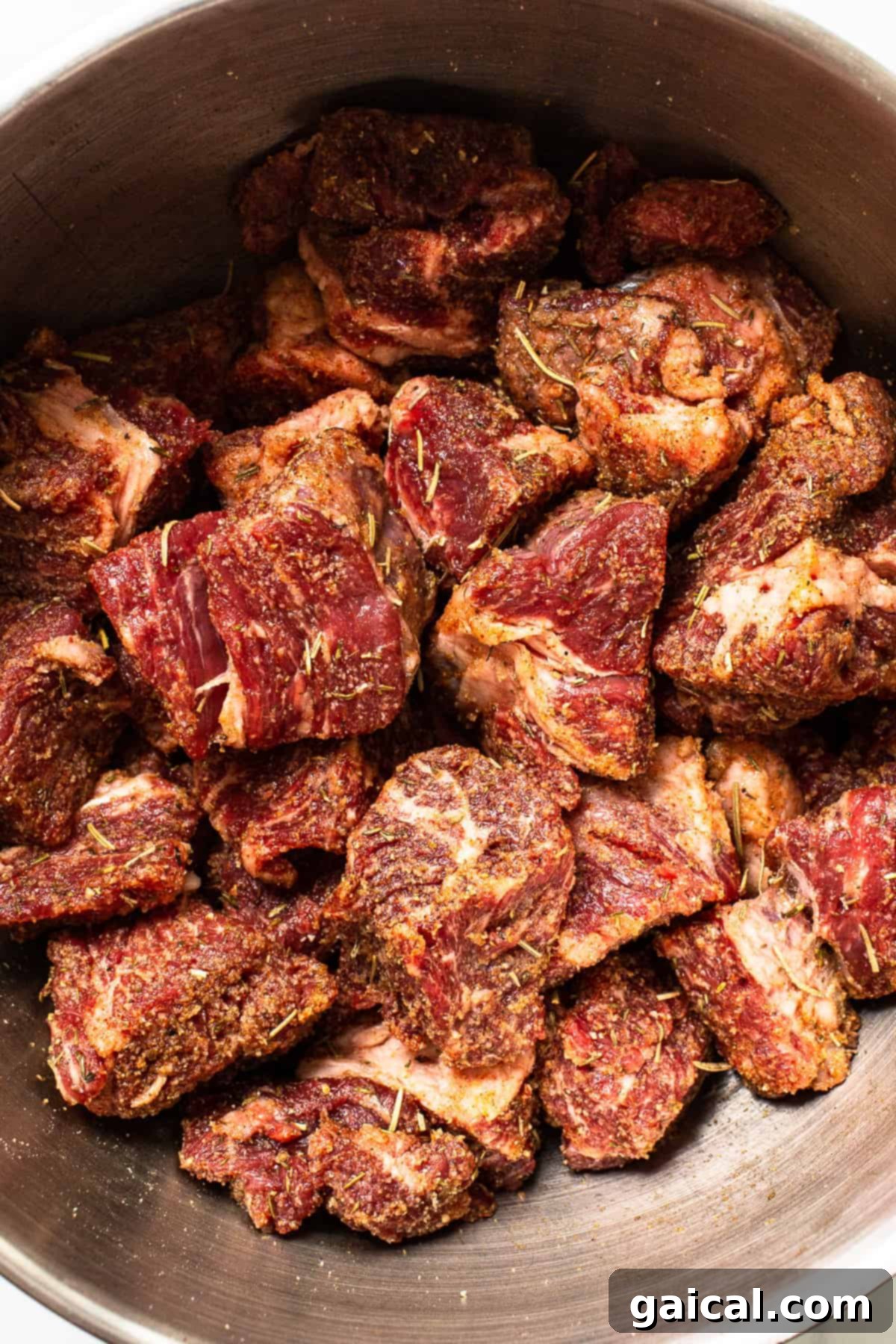 Marbled beef chuck roast chunks being prepared in a pot, seasoned and ready for searing.