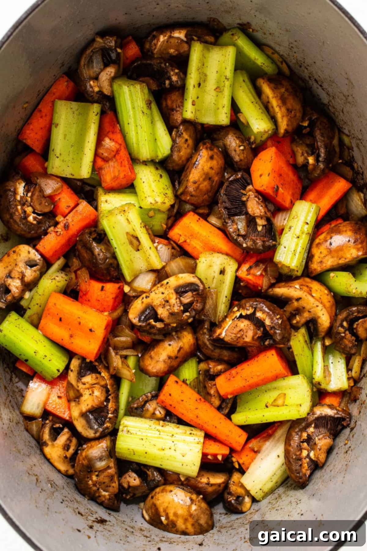 Carrots, celery, and mushrooms simmering in a Dutch oven, part of the rich vegetable base for Guinness beef stew.
