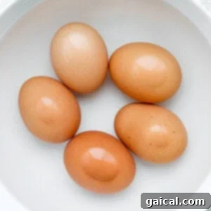 Peeled medium-boiled eggs resting in a bowl of cold water.