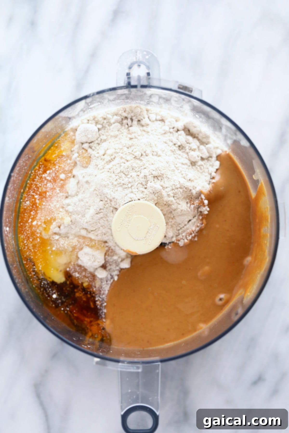 Blending the Perfect Homemade Protein Bar Batter. All the dry and wet ingredients for peanut butter protein bars placed together in a food processor, ready for blending.