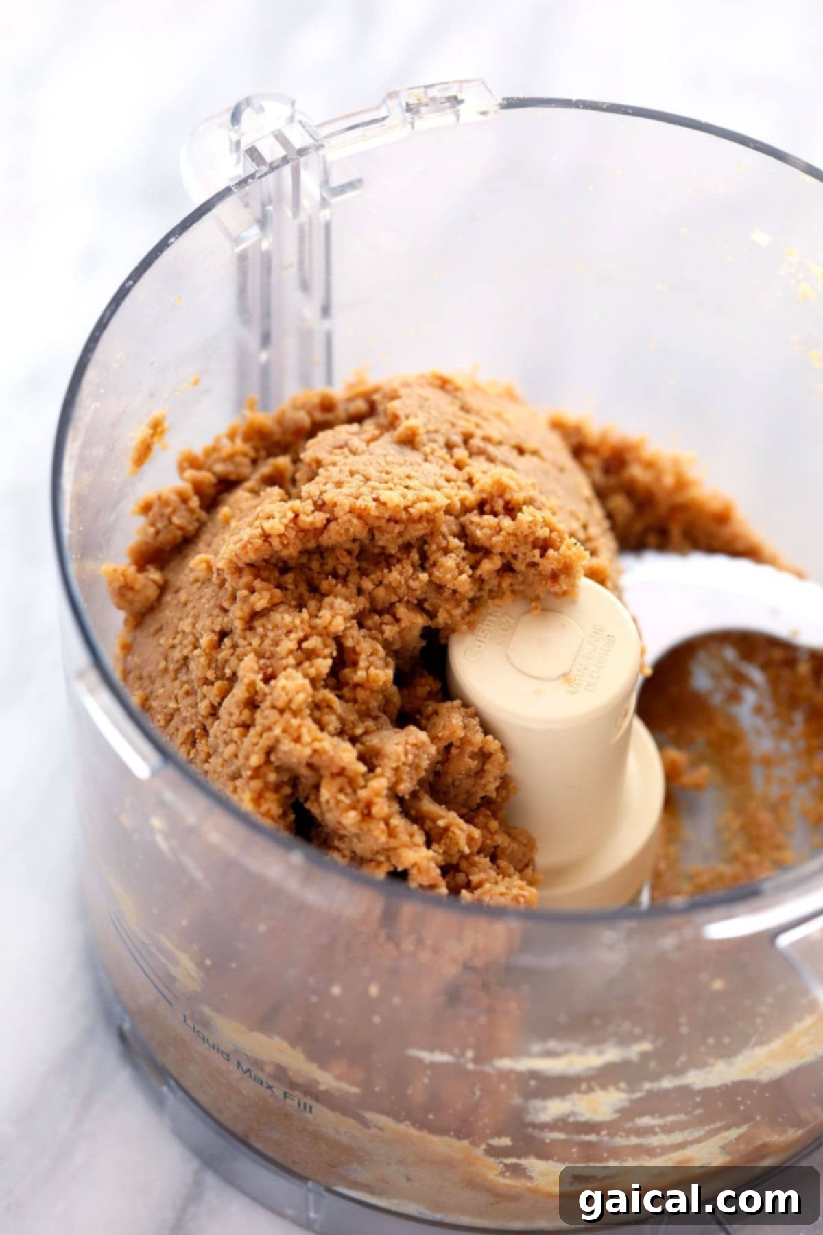 Achieving the Perfect Dough Consistency for Homemade Protein Bars. Thick, creamy peanut butter protein bar dough expertly mixed in a food processor, showcasing its ideal consistency before being pressed into a pan.