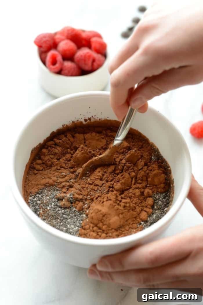 Ingredients for chocolate chia seed pudding being stirred in a bowl.