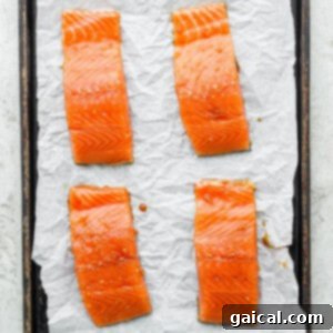 Salmon fillets on a baking sheet, arranged for broiling in the oven.