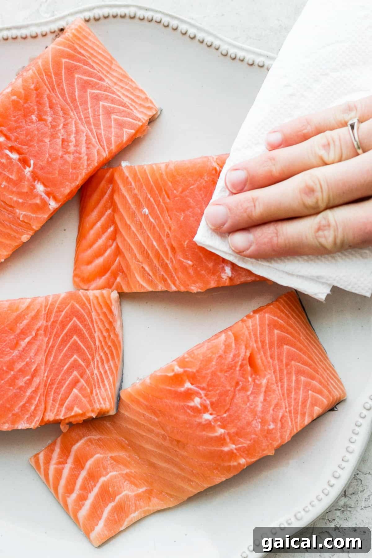 Preparing Salmon for Teriyaki Chef patting salmon fillets dry with a paper towel before marinating.