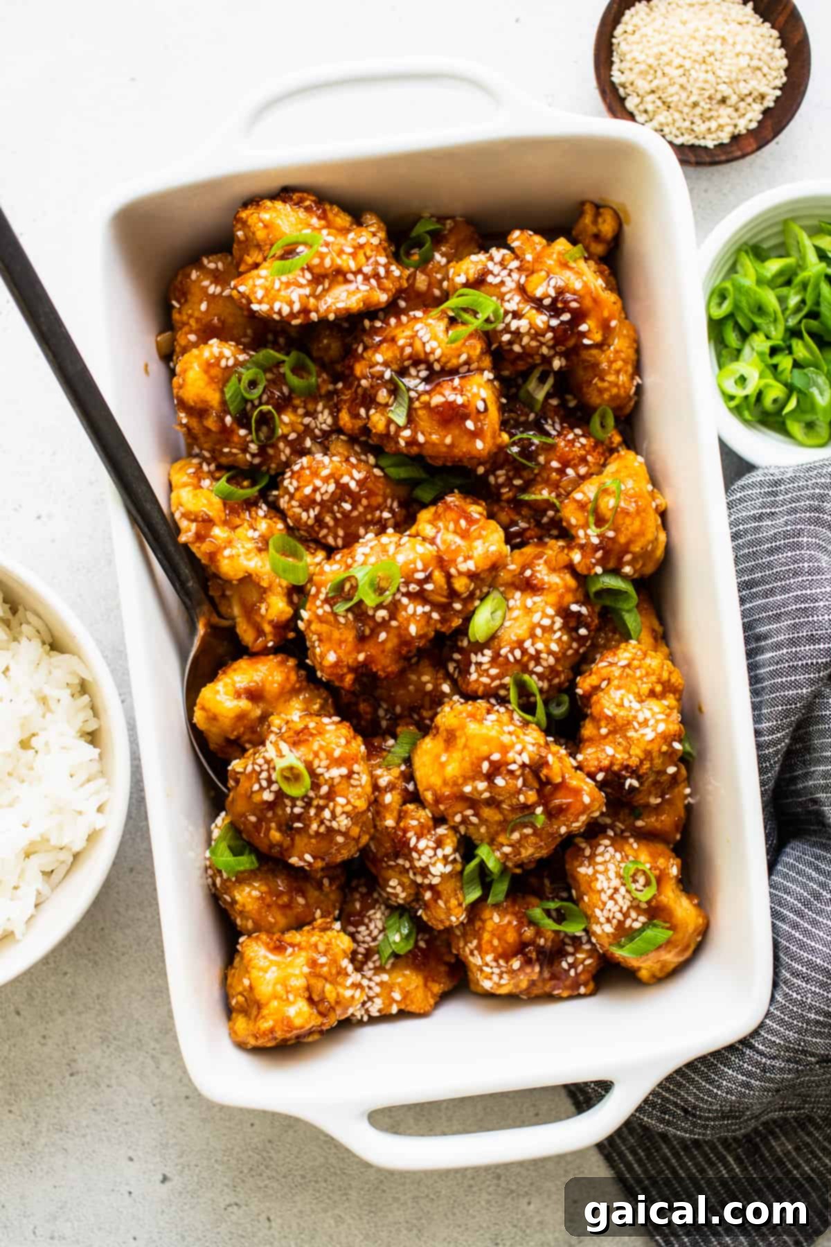 This saucy, delicious air fryer honey sesame chicken is ready in 30 minutes and tastes deep-fried, but it's actually made in the air fryer! honey sesame chicken in dish with sesame seeds