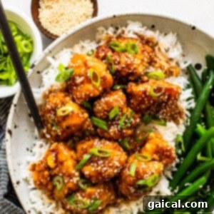 Sweet and Sticky Air Fryer Honey Sesame Chicken 2 A bowl of sesame chicken with rice and green beans.