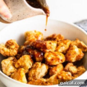 Sweet and Sticky Air Fryer Honey Sesame Chicken 5 adding sauce to chicken