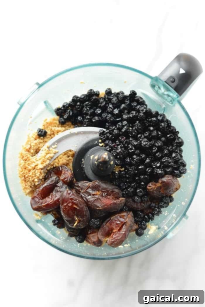 Close-up of a single blueberry cashew truffle, perfectly dipped in dark chocolate and sprinkled with sea salt, on a pristine white surface.