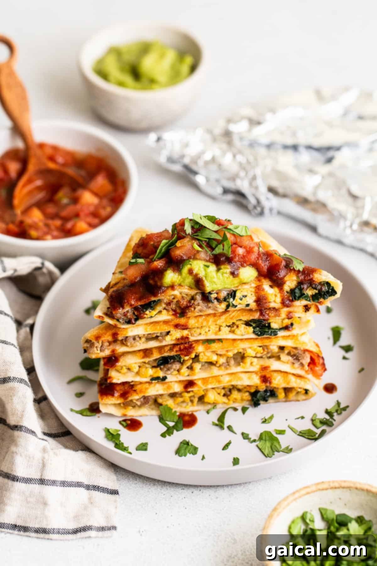 Serving Suggestions and Toppings for Breakfast Quesadillas Slices of make-ahead freezer breakfast quesadillas elegantly arranged on a plate, adorned with vibrant salsa and creamy guacamole.