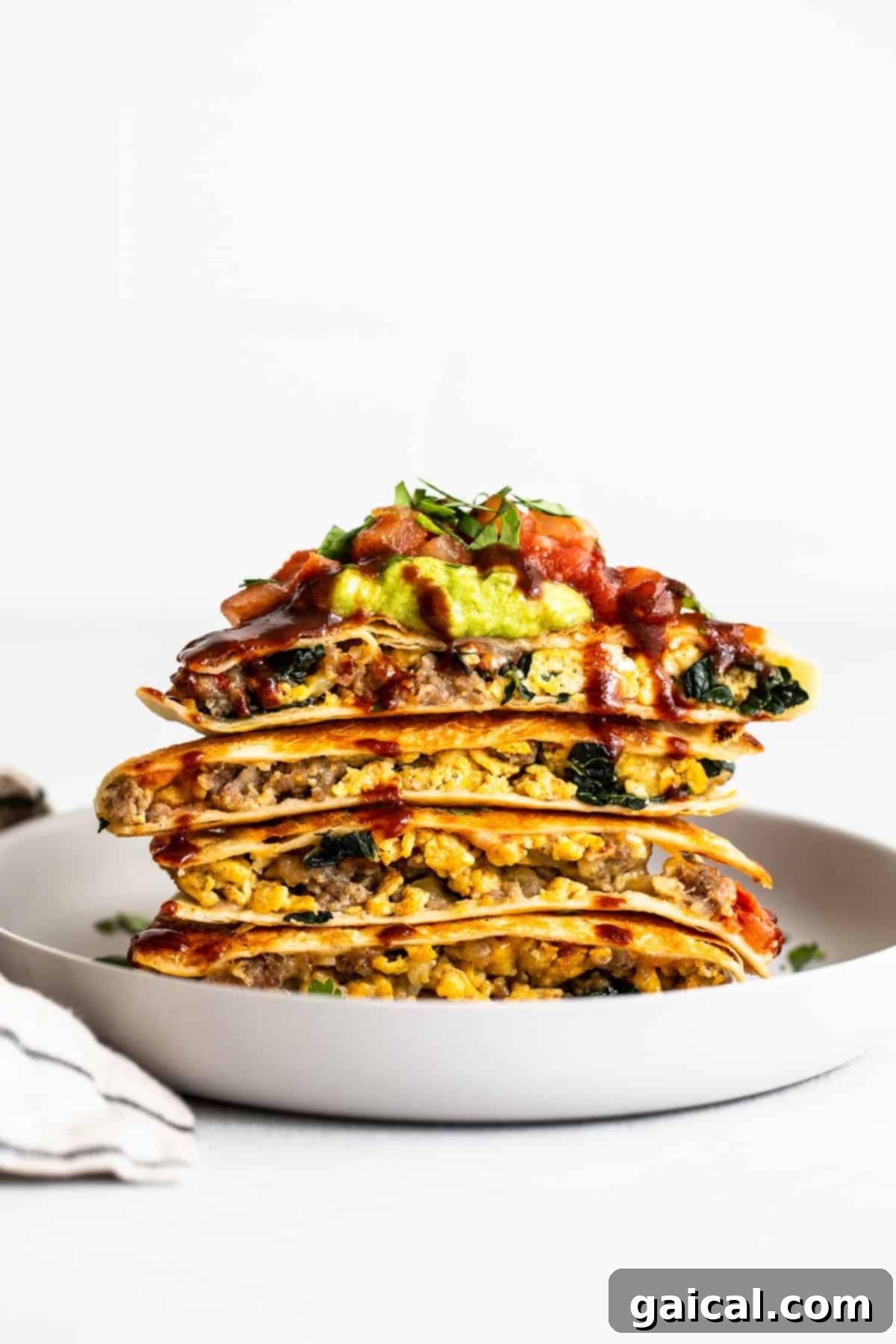 Batch Cook for Delicious Make-Ahead Breakfasts Multiple slices of make-ahead freezer breakfast quesadillas stacked neatly on a white plate, showcasing their inviting layers.