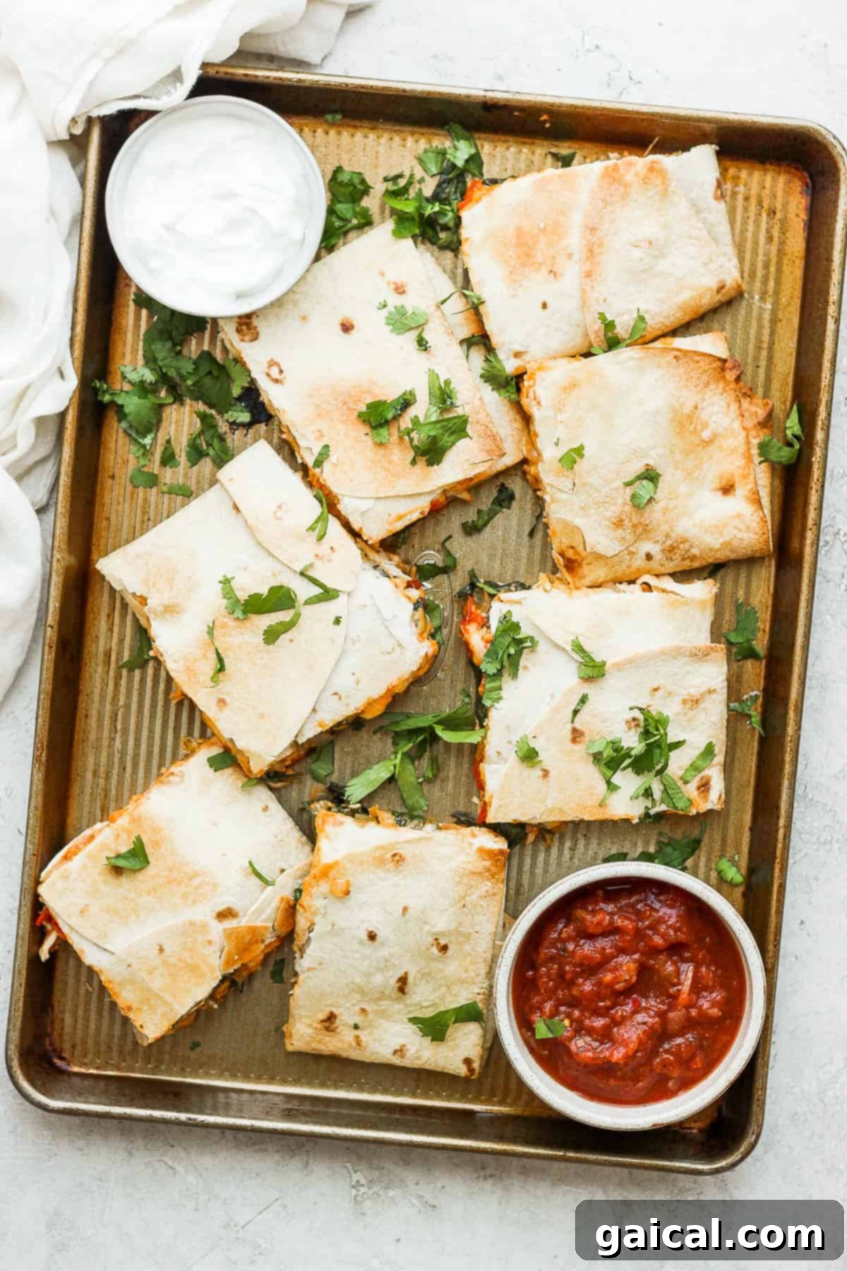 Sheet Pan Quesadilla Party 2 Sheet pan quesadillas topped with fresh cilantro, sour cream, and salsa, ready to be served.