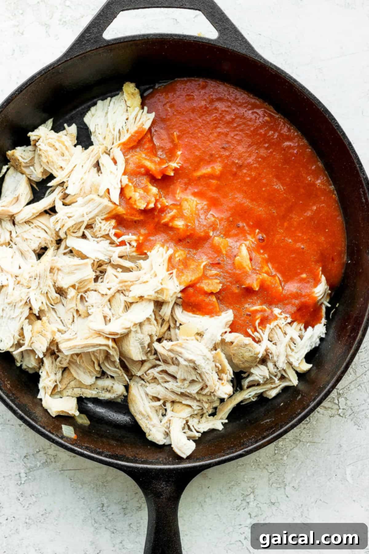 Chicken tinga simmering in a cast iron skillet. Chicken tinga in a cast iron skillet.