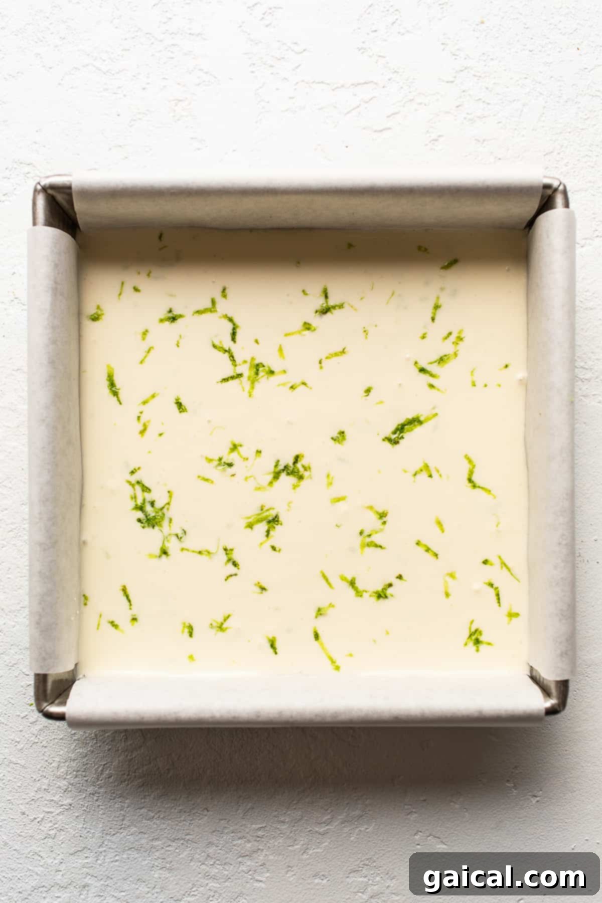 Margarita Pie Bars in a square baking dish, with the creamy filling spread over the pretzel crust, ready for freezing.