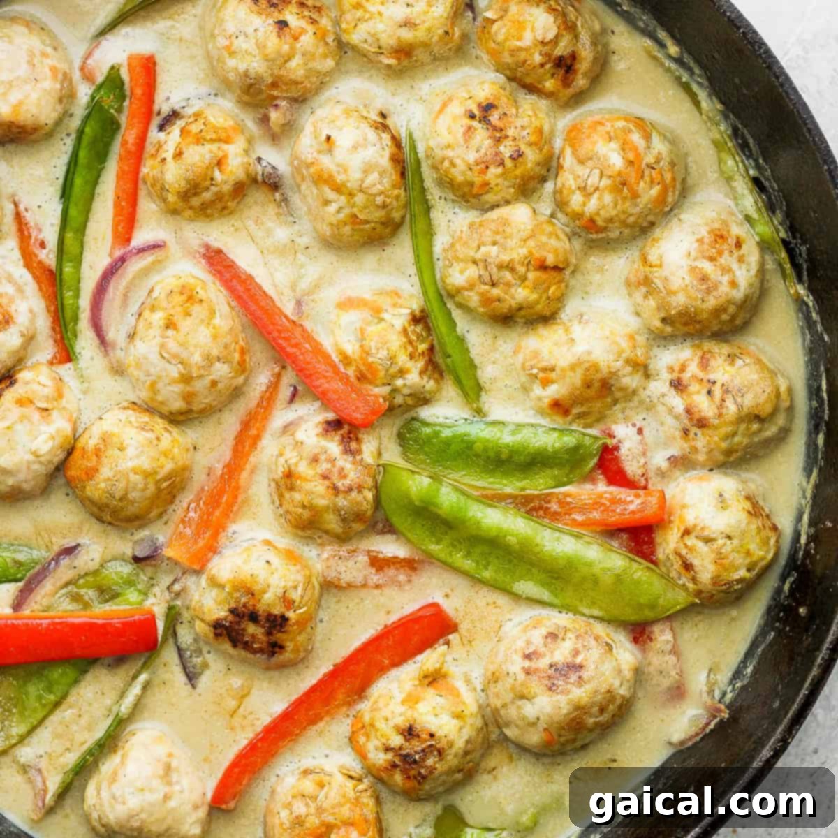Chicken meatballs and vegetables simmering in a cast iron pan.