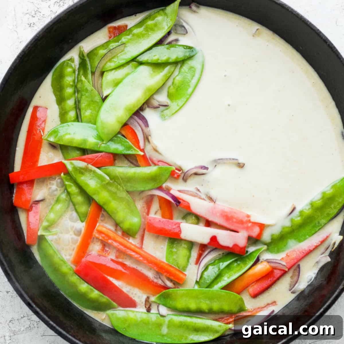 Green curry and vegetables in a cast iron pan.