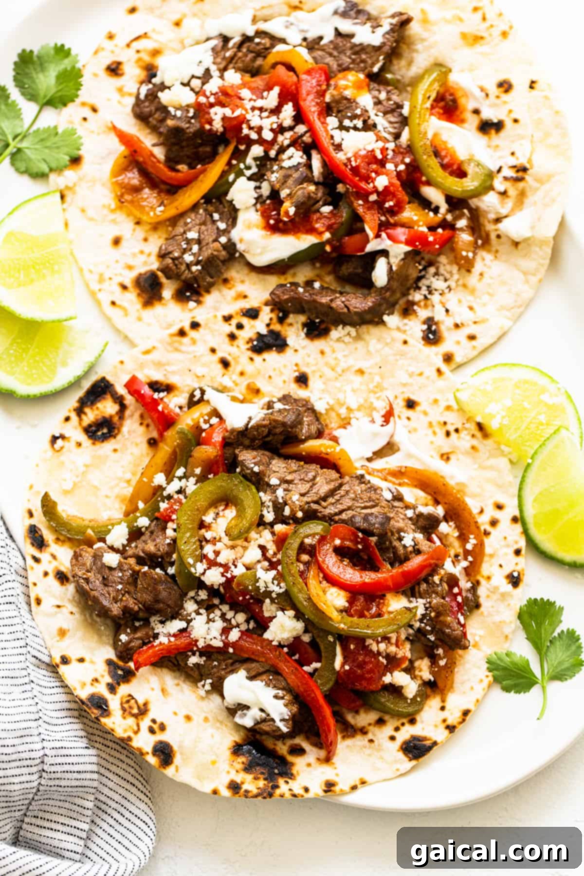 These easy steak fajitas are made from perfectly seasoned sliced flank steak and tossed with colorful fajita veggies. Enjoy! Steak fajitas on a tortilla, ready to be enjoyed.
