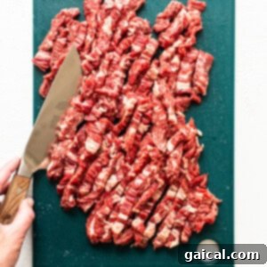 Sizzling Steak Fajitas 8 A person cutting flank steak against the grain on a cutting board.
