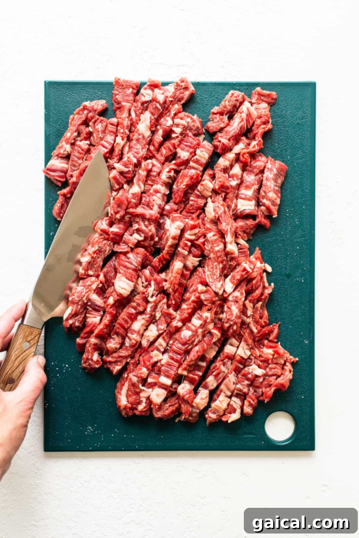 Always be sure to slice the flank steak against the grain of the meat. It helps to tenderize the meat. Sliced flank steak on a cutting board, illustrating the proper slicing technique.