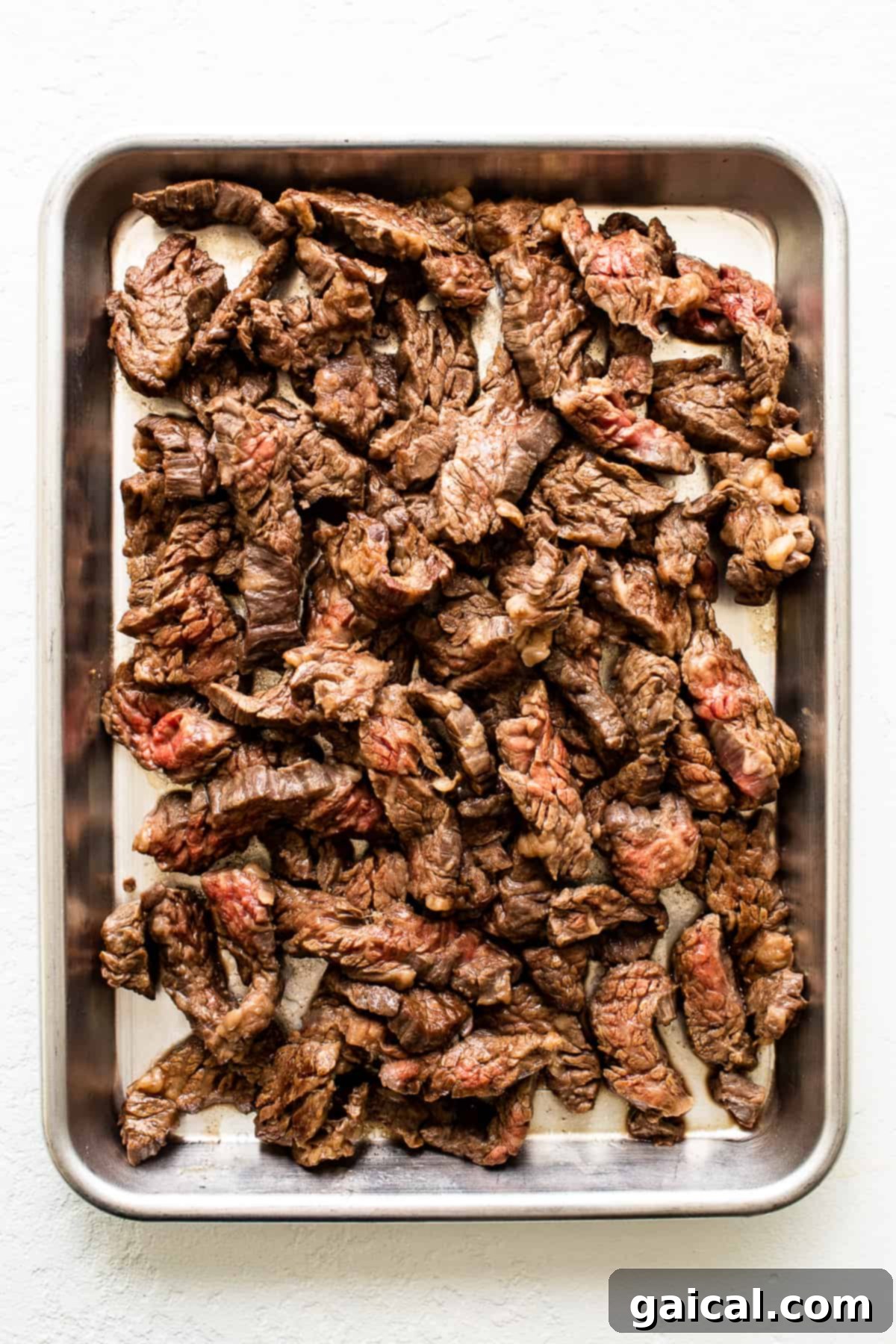 We love serving steak fajitas with tender flank steak strips. Perfectly cooked flank steak slices on a baking sheet, ready for serving.