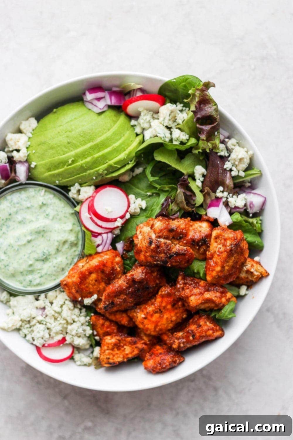 A close-up of Sriracha chicken salad in a bowl, showing the crisp chicken, fresh greens, and creamy dressing.