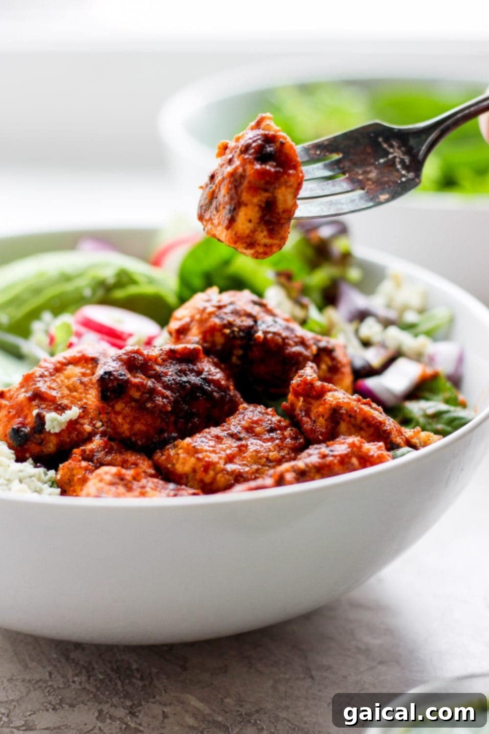 A fork holding a piece of crispy Sriracha chicken, showcasing its golden-brown breading and delicious texture.