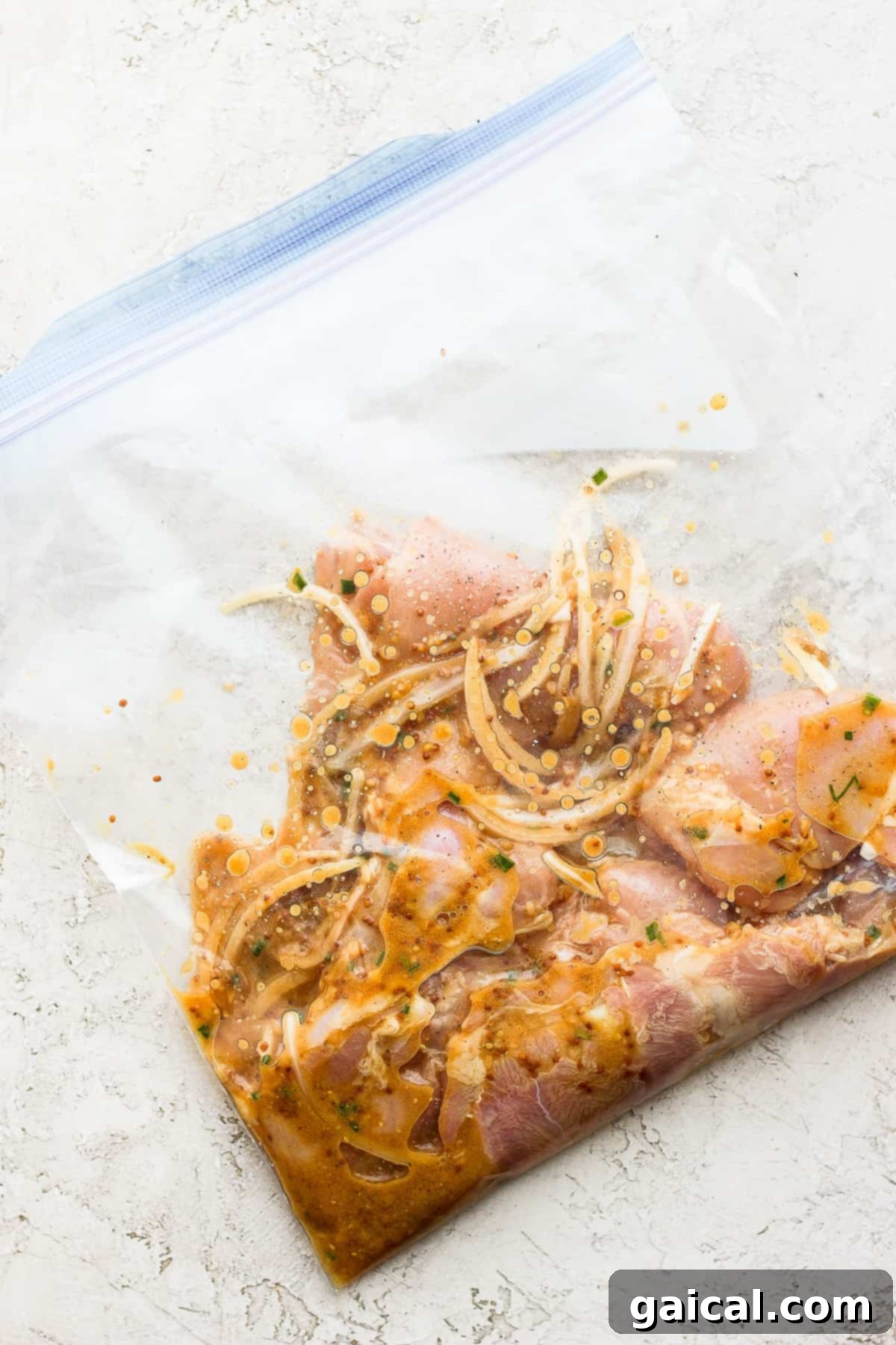 Raw chicken thighs in a gallon-size bag with honey mustard marinade.