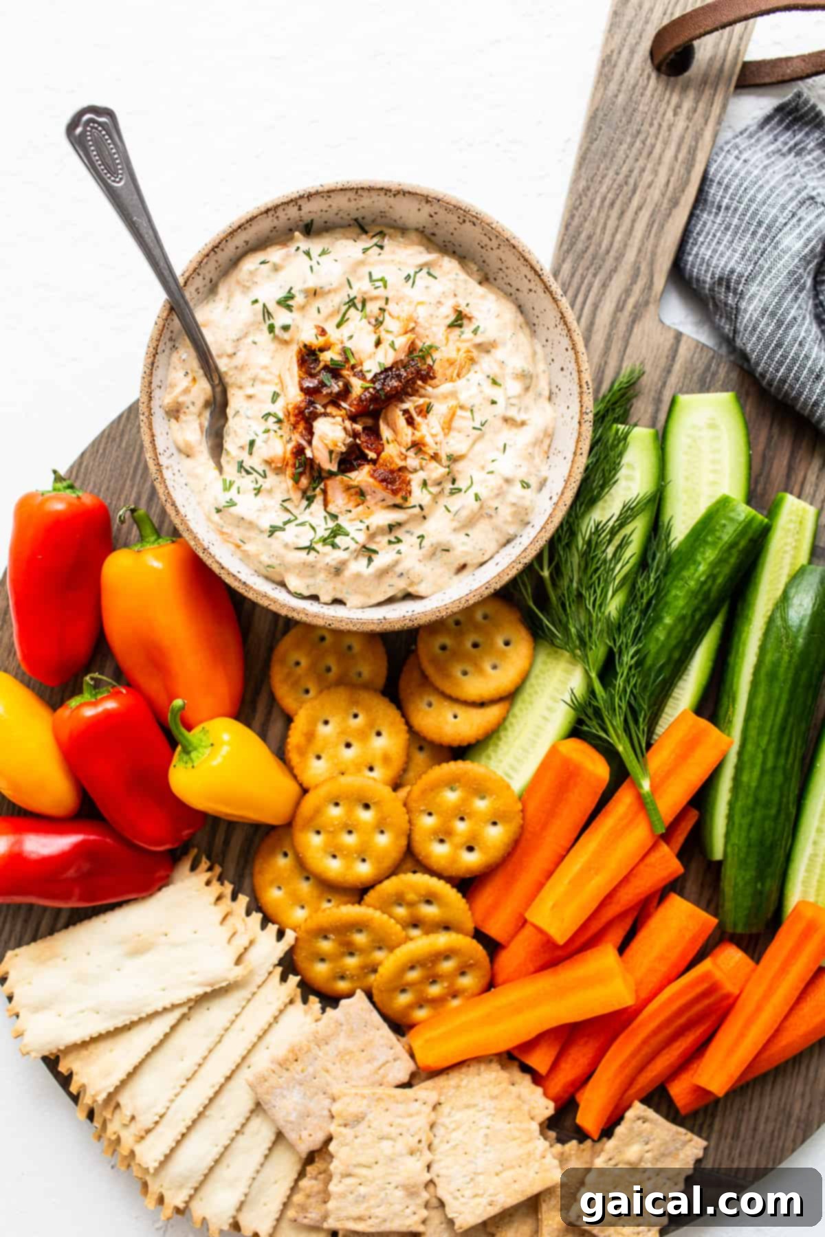Serving Smoked Salmon Dip with a Variety of Accompaniments A generously sized bowl of creamy smoked salmon dip, beautifully garnished with fresh dill, accompanied by a selection of crunchy crackers and crisp vegetable sticks, ready for communal enjoyment.