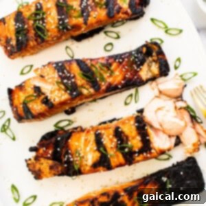 Cooked honey glazed salmon fillet on a white plate, ready to eat.