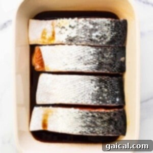 Salmon marinating in a dish with honey ginger soy sauce.